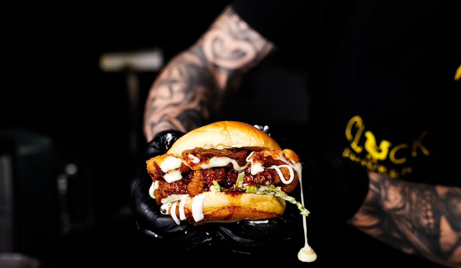 A chicken burger held up in the dark